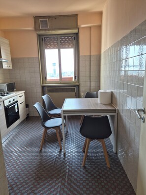 Una cocina compacta con una mesa de comedor, dos sillas, un microondas, una estufa y una ventana con vistas.