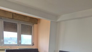 A modern living room with two grey sofas, a small table, and a large window with blinds. - Venice Nice apartment (Venezia)
