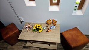 Una mesa de madera con aperitivos, un jarrón de girasoles y un enchufe en la pared.