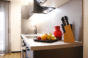 A kitchen with a sink, stove, and a fruit bowl on the counter.