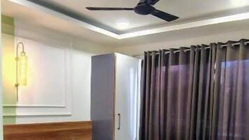 A hotel room with a bed, a ceiling fan, a nightstand, a lamp, and a window with curtains.