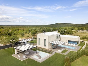 Una casa moderna amb piscina, zona d'estar a l'aire lliure i vistes del paisatge circumdant.