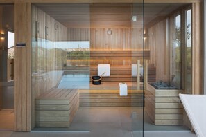 Una sauna moderna con pareti in legno e un’area vetrata, una panca, un asciugamano e una bacinella.
