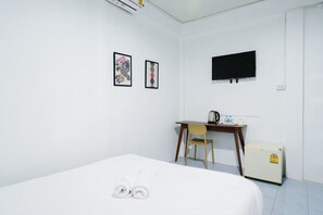 A hotel room with a bed, a desk, a chair, a television, and a small refrigerator. - zNAP Ekkamai (Bangkok)