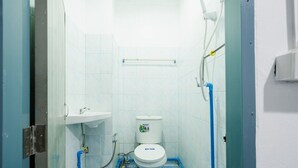 Un baño pequeño y estrecho con un inodoro blanco, un lavamanos y tuberías azules.