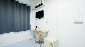 Una habitación pequeña con escritorio, silla y un refrigerador blanco.