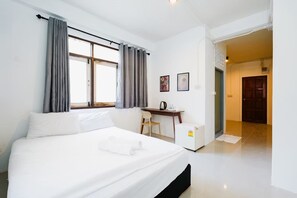 A hotel room with a bed, a desk, a chair, and a refrigerator. - zNAP Ekkamai (Bangkok)