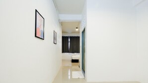 Un pasillo con una cama, una puerta y una ventana con cortinas.