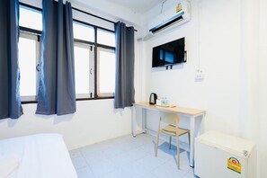 A room with a bed, a desk, a chair, a TV, and an air conditioner. - zNAP Ekkamai (Bangkok)