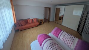 A room with a sofa, a bed, a wardrobe, and a mirror. - Sonneck vacation apartment for 4 people with direct access to the garden. (Feldberg (Schwarzwald))