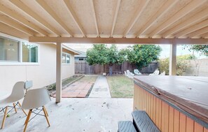 Eine überdachte Terrasse mit Grillplatz, Gartenmöbeln und einem Holzboden.