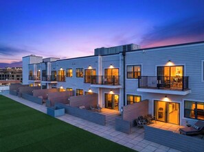 Un edificio residencial de varios pisos con balcones, área de estar al aire libre y una entrada bien iluminada.
