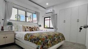Ein Schlafzimmer mit Bett, Nachttisch, Kleiderschrank und Klimaanlage.