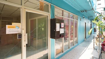 Entrada d'hotel amb una porta de vidre, un sistema d'entrada per codi numèric i un codi QR per accedir-hi digitalment.