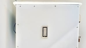 A white, square-shaped, wall-mounted device with a keypad and a small window, likely a security or intercom system. - AT Pranakorn (Bangkok)