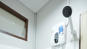 Een badkamer met witte betegelde wanden, een douche met handdouche en een witte pijp.