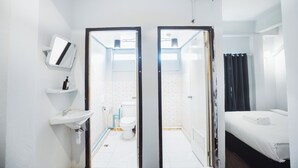 A compact hotel room with a bathroom, a bed, and a small window. - AT Pranakorn (Bangkok)