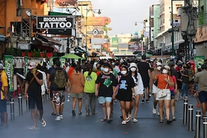 A crowded street with various shops and signs, including a tattoo parlor. - AT Pranakorn (Bangkok)
