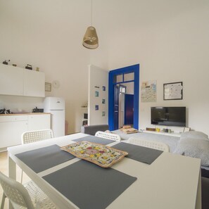 A compact living space with a kitchenette, a dining area, a bed, and a television.