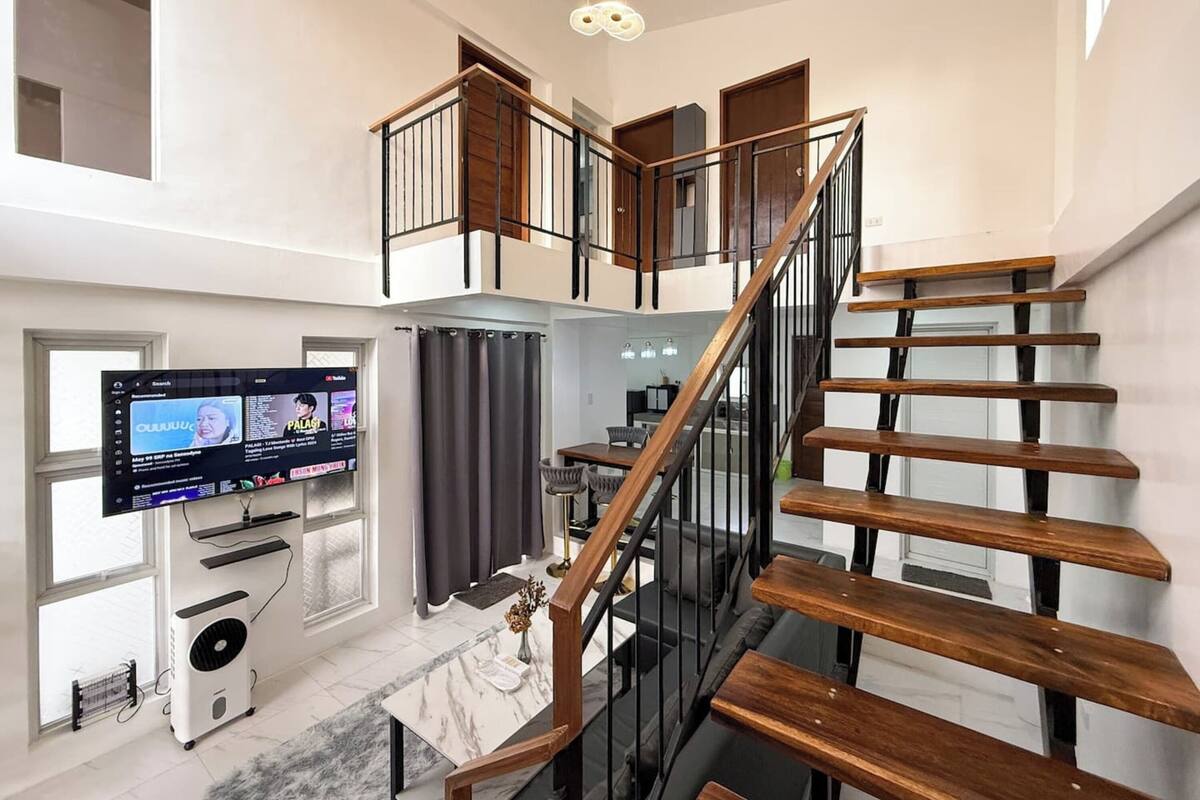 A modern interior with a staircase, a flat-screen TV, and a fan.