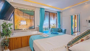 Habitación de hotel con cama, bañera, sofá y vista a las montañas.