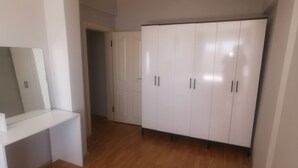 A room with a white wardrobe, a white desk, and a wooden floor. - Quiet and Comfortable in Sinop Karakum Site 2 (Sinop Merkez)