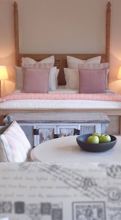 A bedroom with a four-poster bed, a bedside table with a bowl of apples, and a lamp on either side of the bed.. Stylish Studio in Reedy Creek