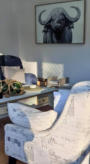 A room with a bed, a desk, a chair, and a framed artwork on the wall.