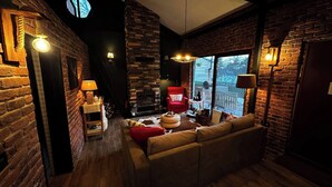 Una habitación acogedora con chimenea, un sillón rojo, un sofá y vistas al exterior.