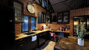 Una cocina con paredes de ladrillo, encimera de madera, un reloj y una planta en maceta.