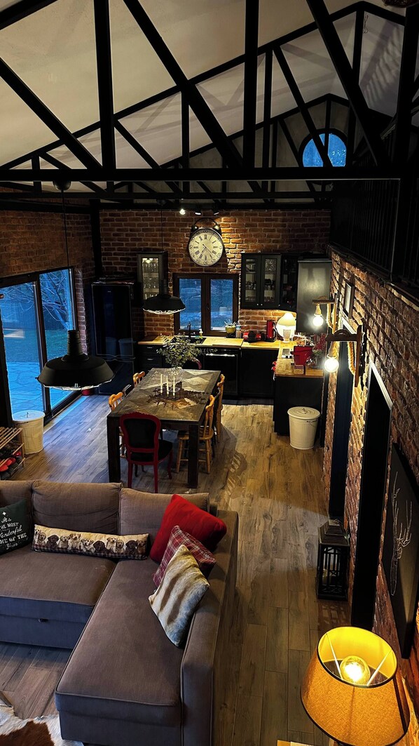 A spacious living area with a fireplace, a dining table, and a kitchen in the background.
