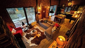 Un salón tipo loft con un ventanal grande, una chimenea, un comedor y una cocina visible a través de una puerta abierta.