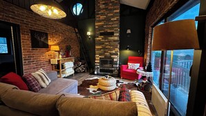 Un salón acogedor con chimenea, un sofá rojo, una mesa de centro de madera y un ventanal grande.