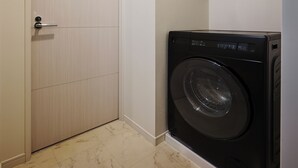 A laundry room with a closed door, a washing machine, and a small shelf. - Residence Hotel Hakata Station2 (Fukuoka)