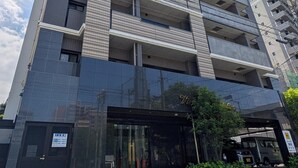 A multi-story building with a modern architectural design, featuring a glass entrance and a visible sign indicating a business establishment. - Residence Hotel Hakata Station2 (Fukuoka)