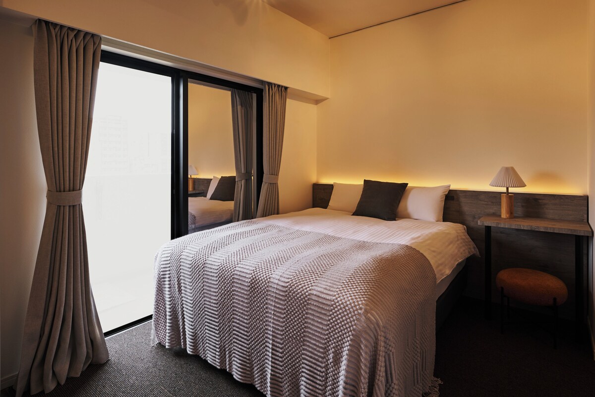 Una habitación de hotel con una cama grande, un escritorio con lámpara y una silla.