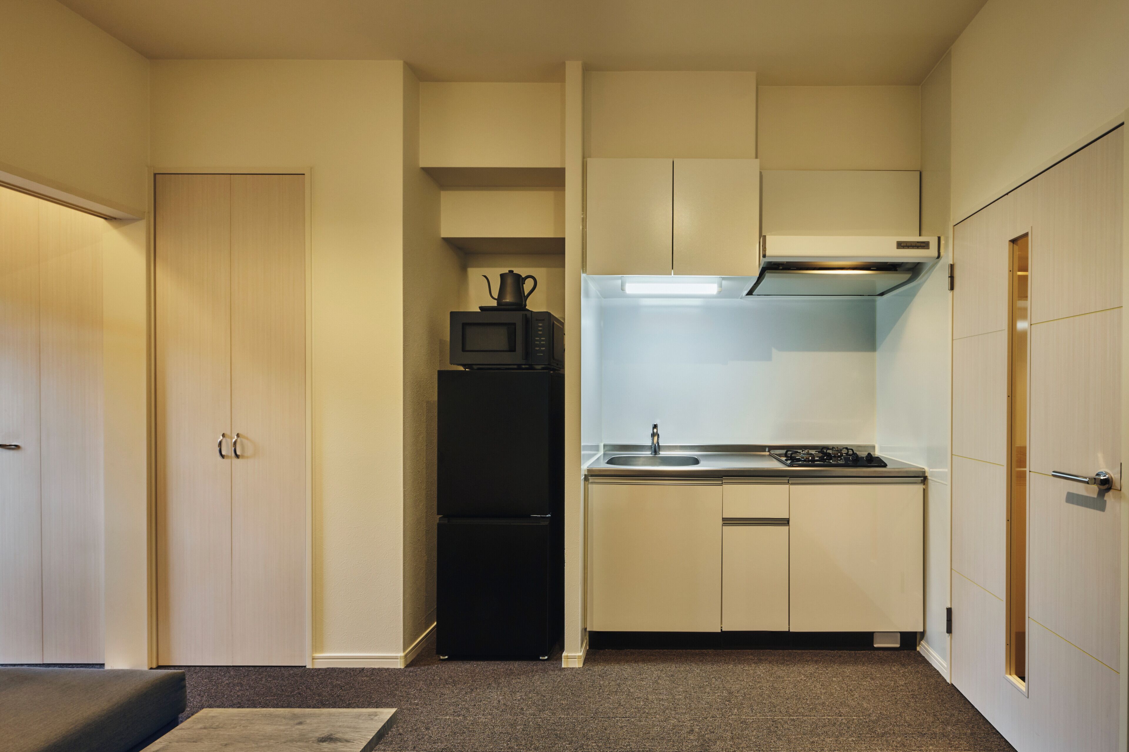 A compact kitchen with a refrigerator, microwave, stove, and a small sink.