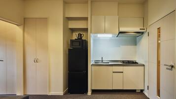 A compact kitchen with a refrigerator, microwave, stove, and a small sink.
