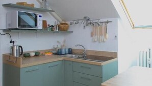 A kitchen with a microwave, sink, and wooden countertop. - Piccolo Attico - Wi-Fi (Turin)