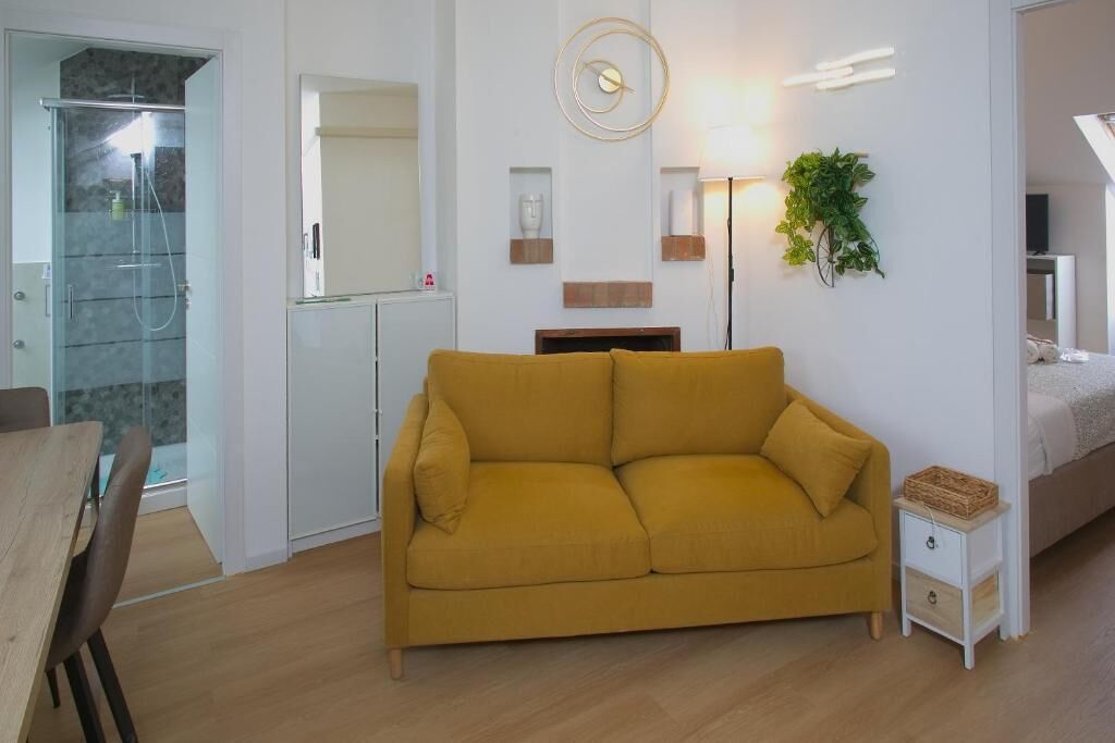 Una sala moderna con un sofá, una mesita, una mesilla de noche, una lámpara y una planta.