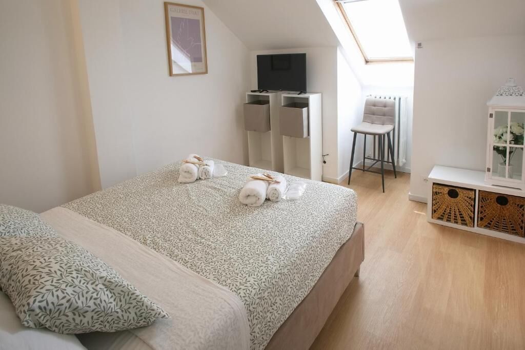 A bedroom with a bed, a desk, a chair, and a TV.