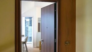 A wooden door leading to a room with a visible window and a dining area with chairs. - Piccolo Attico - Wi-Fi (Turin)