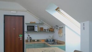 A compact kitchen with a microwave, sink, and wooden cabinets. - Piccolo Attico - Wi-Fi (Turin)