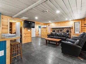 A log cabin interior with a living area, a kitchen, and a fireplace. - Quaint 3-bedroom Boyne City Cabin/ 3-Minutes to Boyne Mountain (Boyne City)