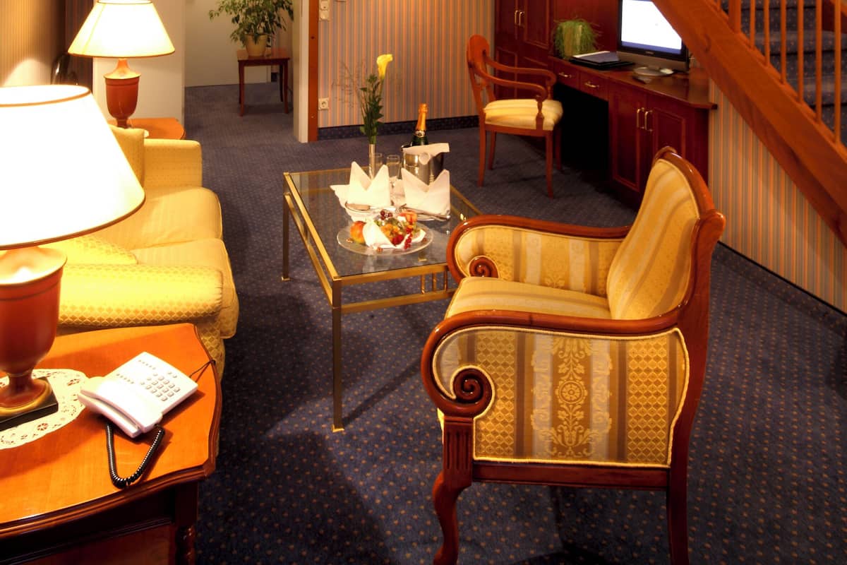 A hotel room with a living area, a staircase, a desk with a computer, and a telephone.