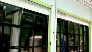 Ein Gebäude mit großen Glasfenstern und einer grünen Tür.