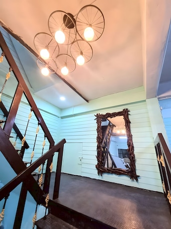 A staircase with a wooden handrail and a unique ceiling light fixture.. Bob House Khaosan