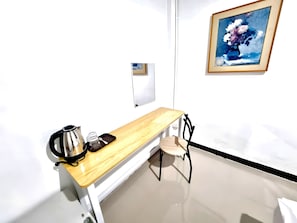 A small room with a wooden desk, a chair, a coffee maker, and a framed painting on the wall. - Bob House Khaosan (Bangkok)