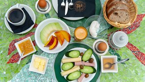 Aamiastarvikkeilla katettu pöytä, jossa on muun muassa munia, leipää, hedelmiä ja erilaisia lisukkeita.