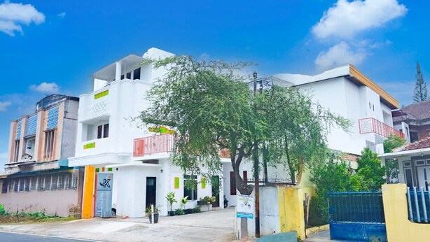 A white building with balconies, a gated entrance, and a tree in front. - Luxury Deluxe DBL Retreat W/ Free WiFi and Parking (Bandar Lampung)